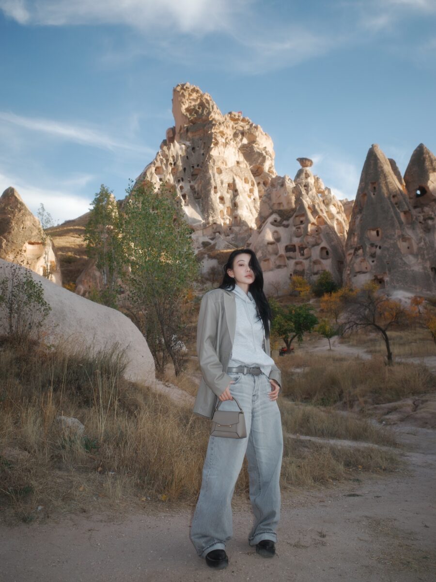 Jessica Wang wearing a light neutral suit among the rock formations of Cappadocia