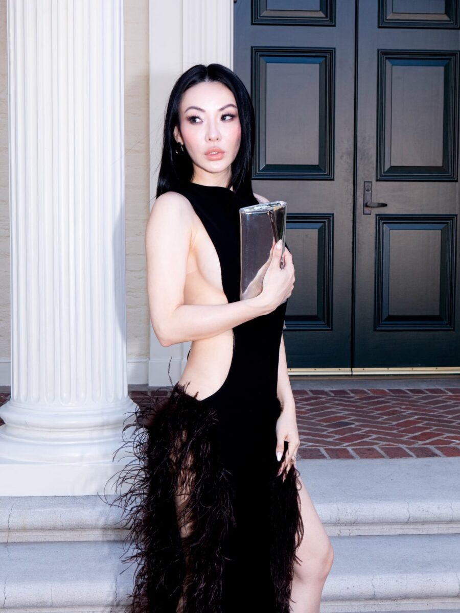 Jessica Wang wearing a black feather-trim designer dress and holding a silver clutch