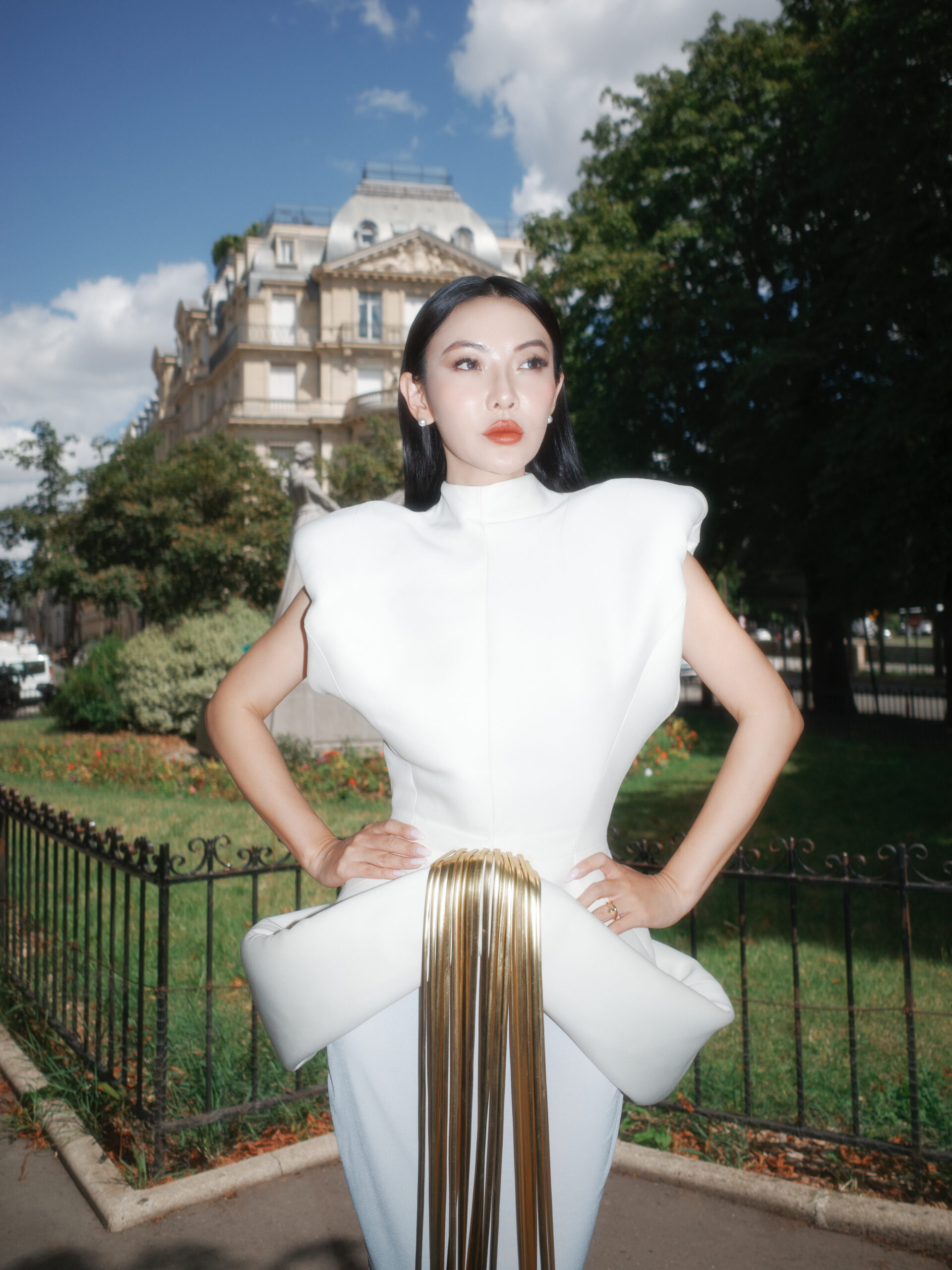 Jessica Wang wearing a white sculptural gown with a gold fringe detail outdoors
