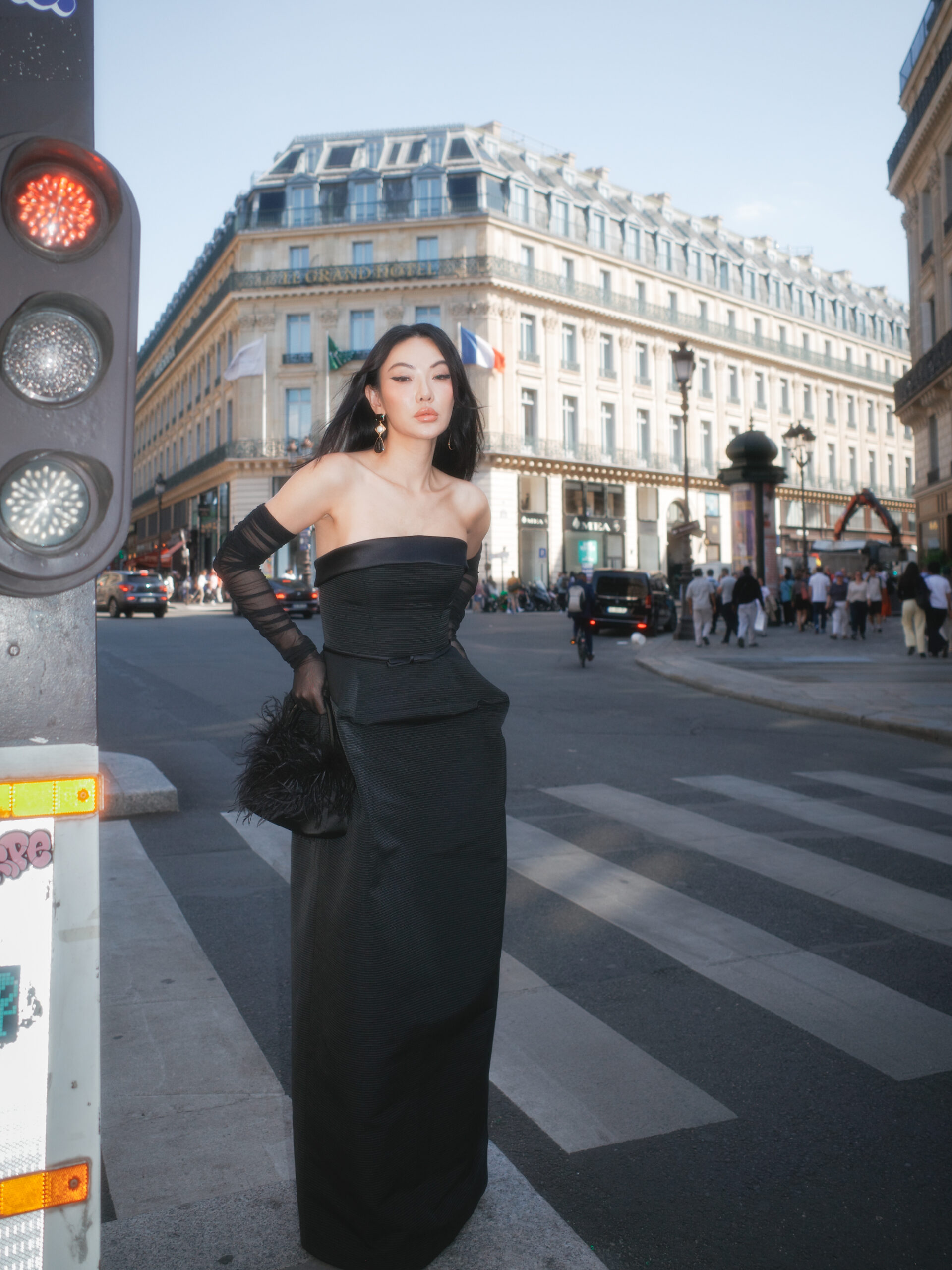 Jessica Wang wearing a black strapless gown with sheer gloves on a city street