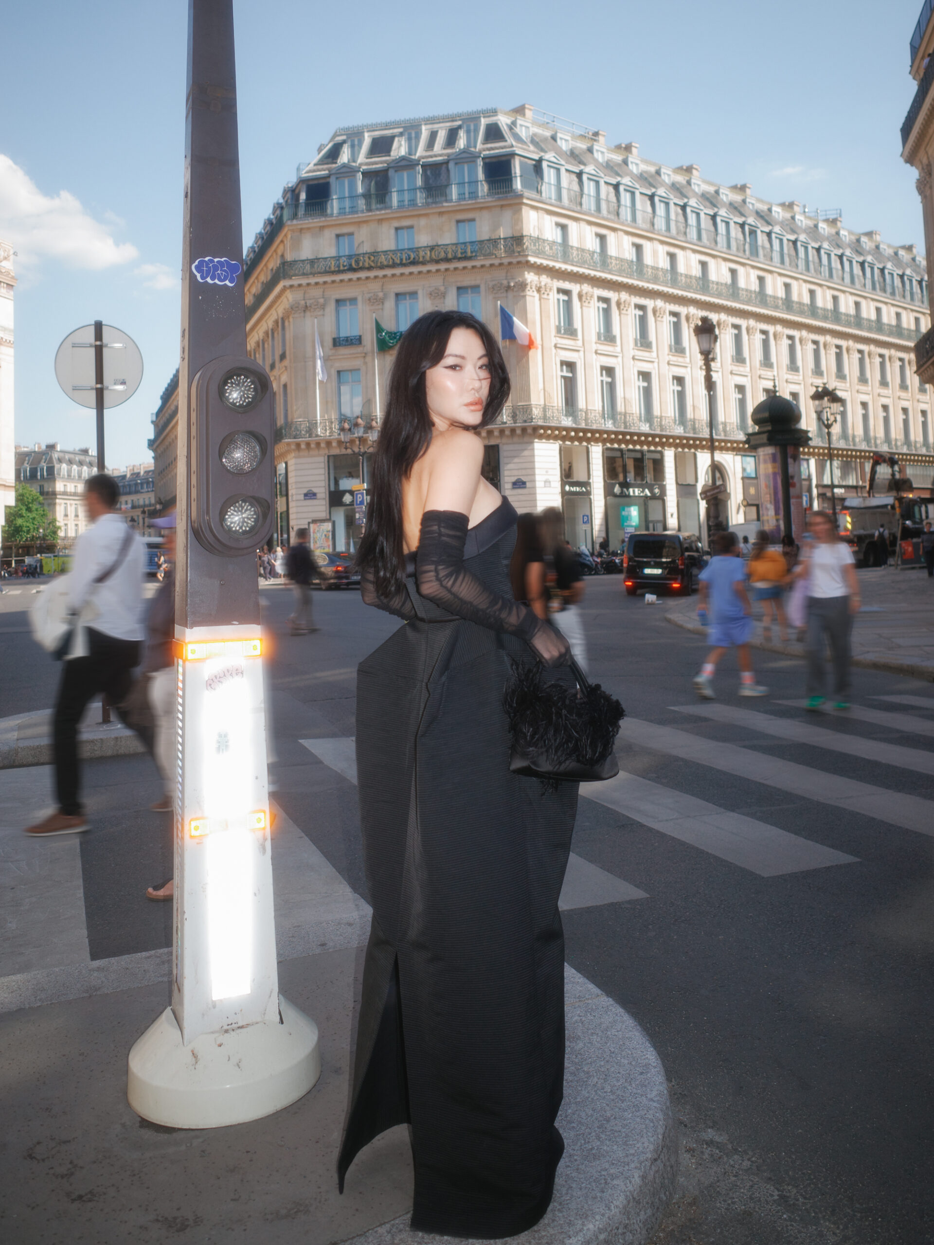 Jessica Wang wearing a floor-length black strapless gown and sheer gloves on a Paris street