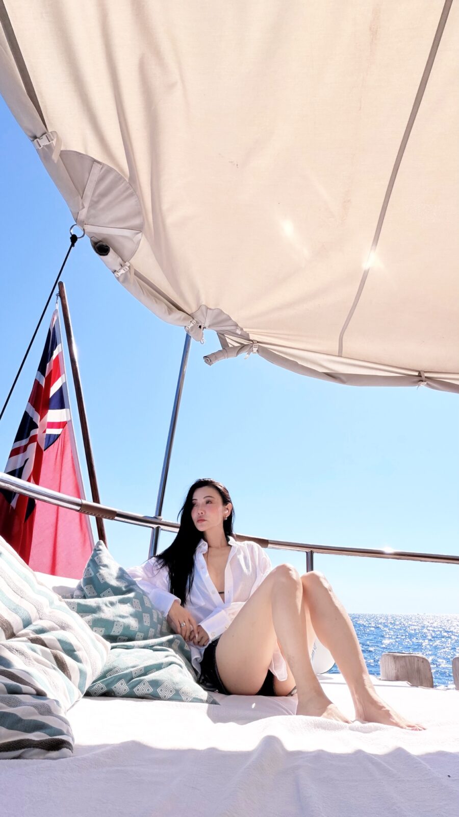 Jessica Wang sitting on a yacht in a white shirt with the sea behind her